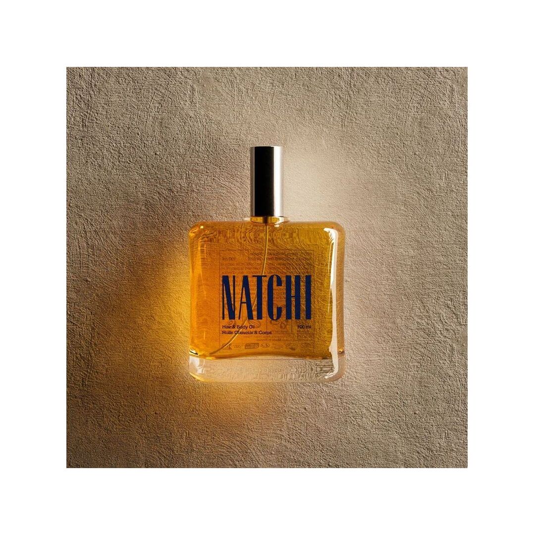 NATCHI Organic Hair & Body Oil bottle against a textured background, showcasing its natural ingredients and elegant design.