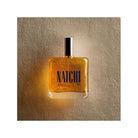 NATCHI Organic Hair & Body Oil bottle against a textured background, showcasing its natural ingredients and elegant design.
