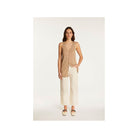 Femme portant un gilet léger à manches courtes en lin flammé, associé à un pantalon blanc, look estival chic.