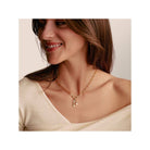 Femme souriante portant le collier Charm Paperclip en or avec Connect Link et breloques, élégant et raffiné.