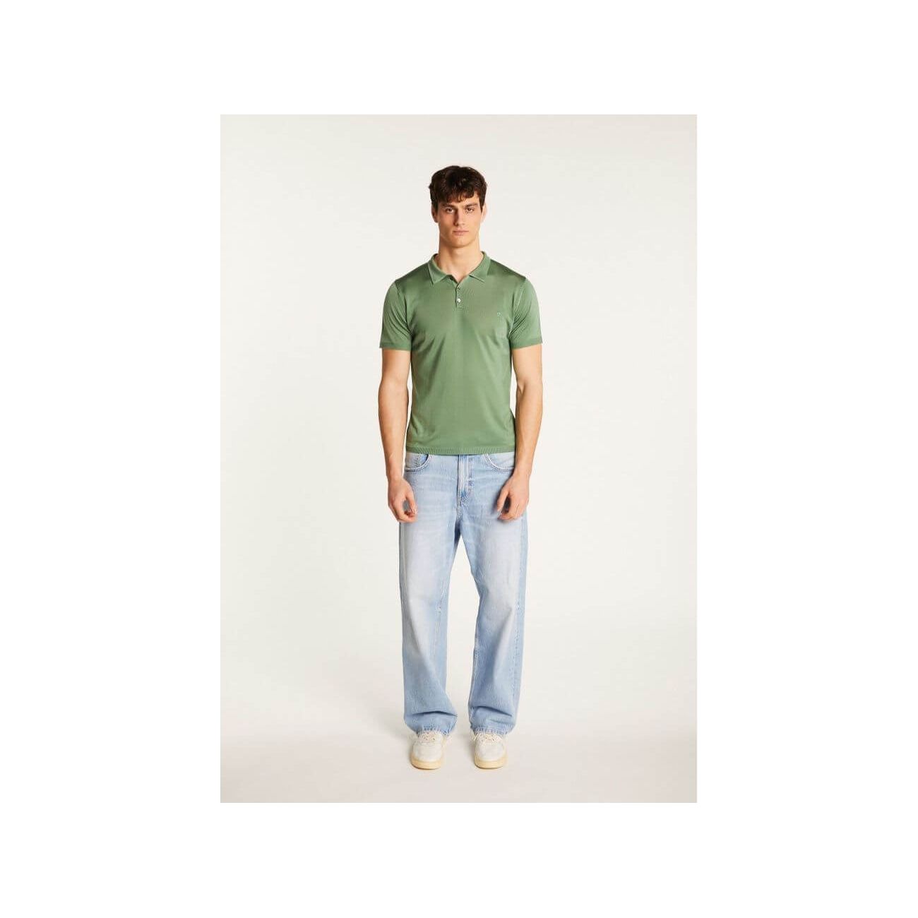 Homme portant un polo fil lumière Babar vert avec jeans clairs, alliant confort et élégance.