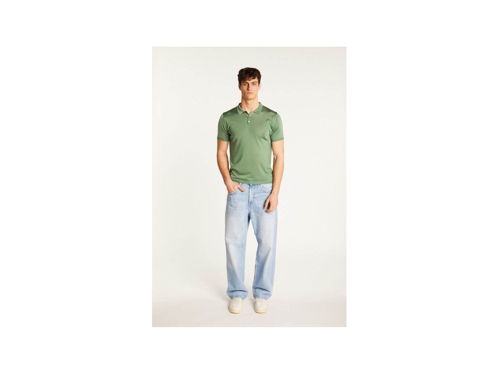 Homme portant un polo vert en Fil lumière Babar avec des jeans clairs et des baskets, look décontracté et élégant.