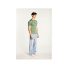 Homme portant un polo vert en fil lumière avec jeans clairs pour un look élégant et décontracté.