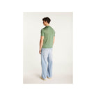 Homme portant un polo vert Fil lumière Babar, vu de dos, associé à un pantalon décontracté en denim.