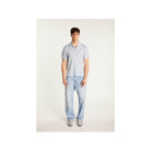 Model wearing the Matthew short-sleeve shirt in blue, paired with light jeans for a casual summer look.