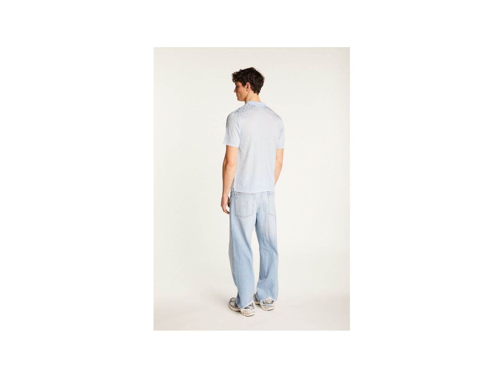 Homme portant une chemise légère et moderne avec un pantalon en jeans, vu de dos.