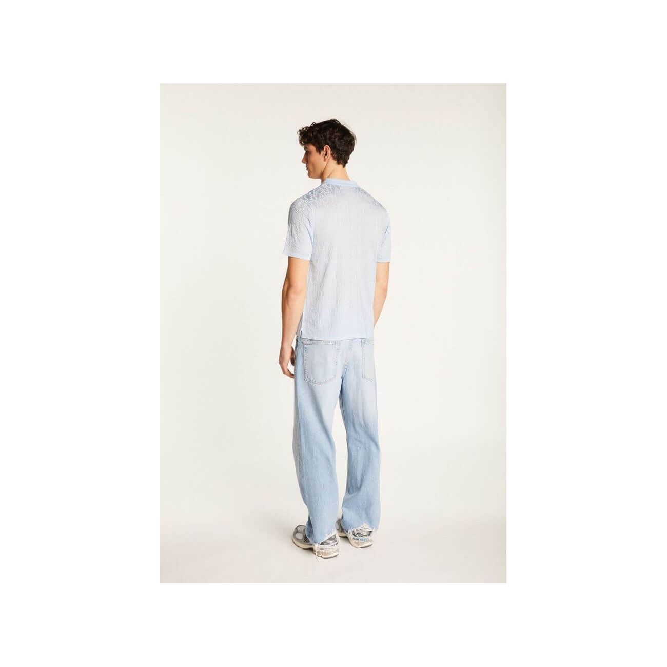 Homme portant une chemise légère et moderne avec un pantalon en jeans, vu de dos.