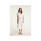 Femme portant la robe Emy en lin blanc, élégante et respirante, parfaite pour un look chic et décontracté.