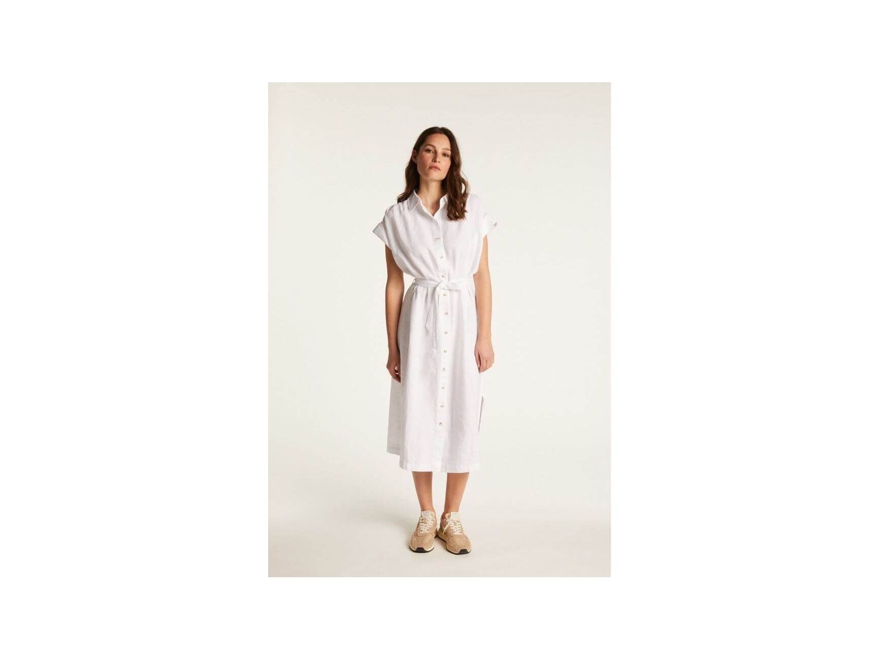 Femme portant la robe Emy en lin blanc, élégante et respirante, parfaite pour un look chic et décontracté.