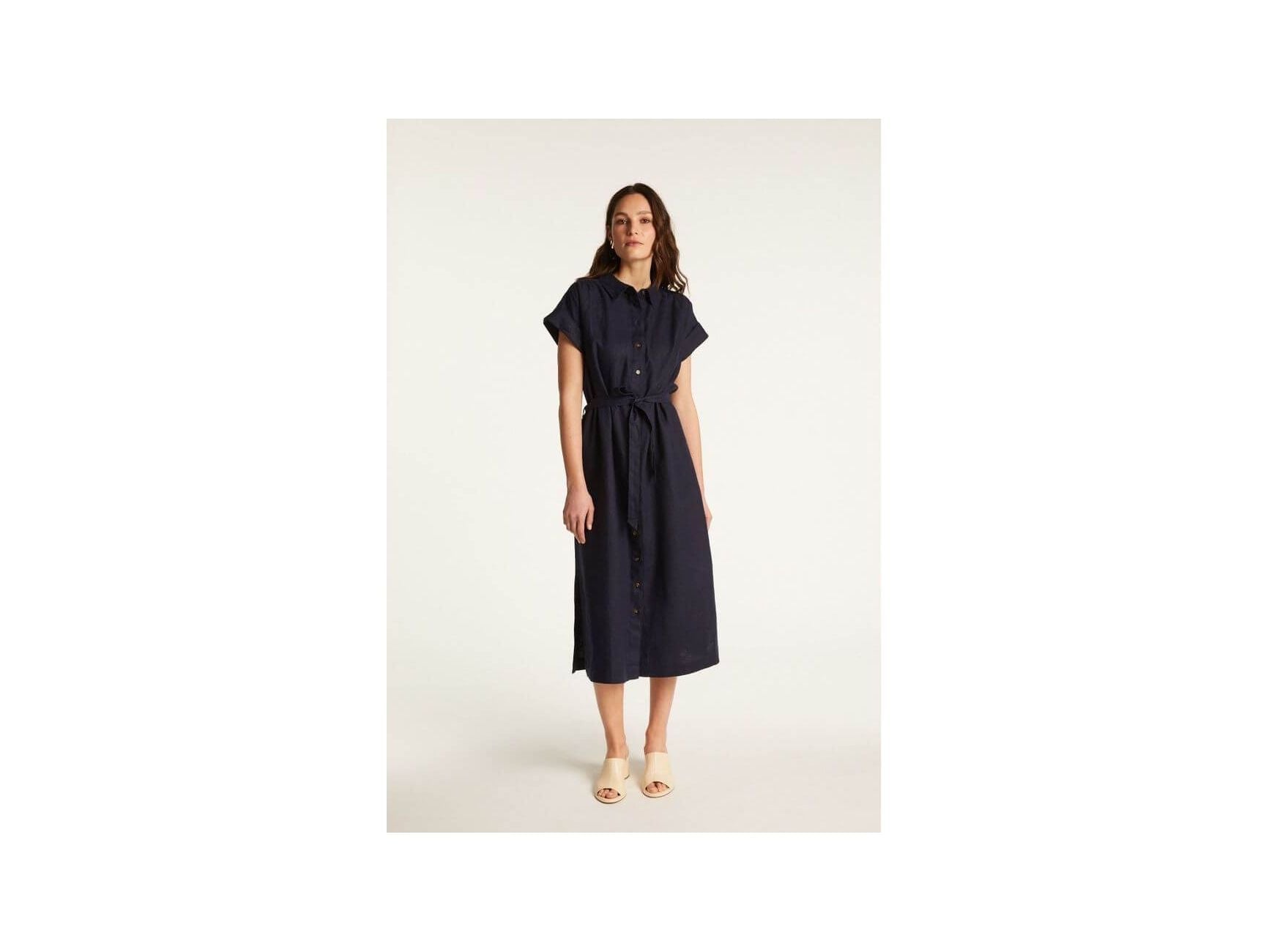 Femme portant la robe Emy, élégante et confortable, en lin léger, avec une coupe fluide et des manches courtes.