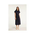 Femme portant la robe Emy, élégante et confortable, en lin léger, avec une coupe fluide et des manches courtes.