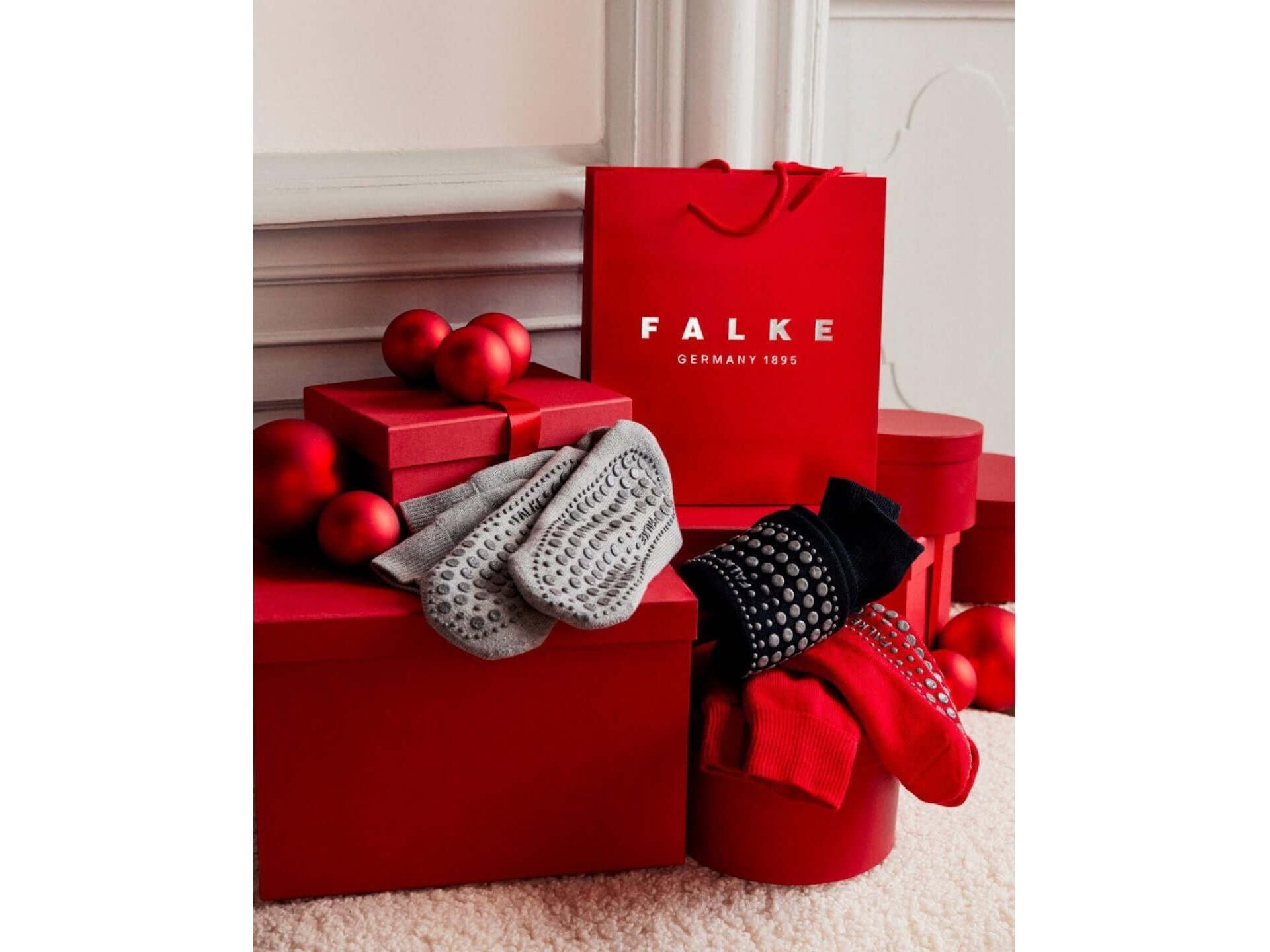 Chaussettes Homepads FALKE en textures grises, noires et rouges, présentées avec des boîtes rouges et boules décoratives.