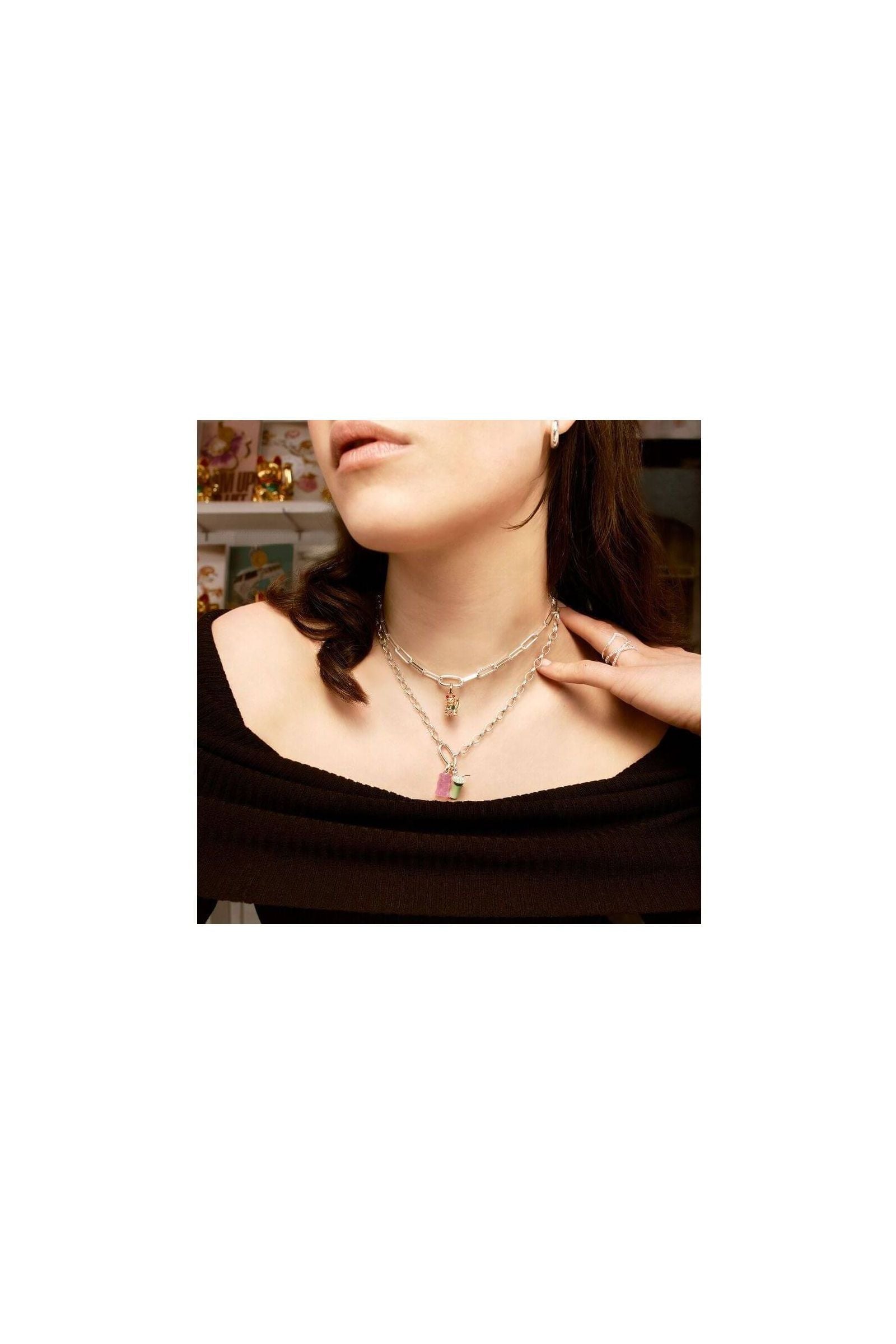 Woman wearing layered silver necklaces with matcha latte charm pendant, showcasing trendy jewelry style.