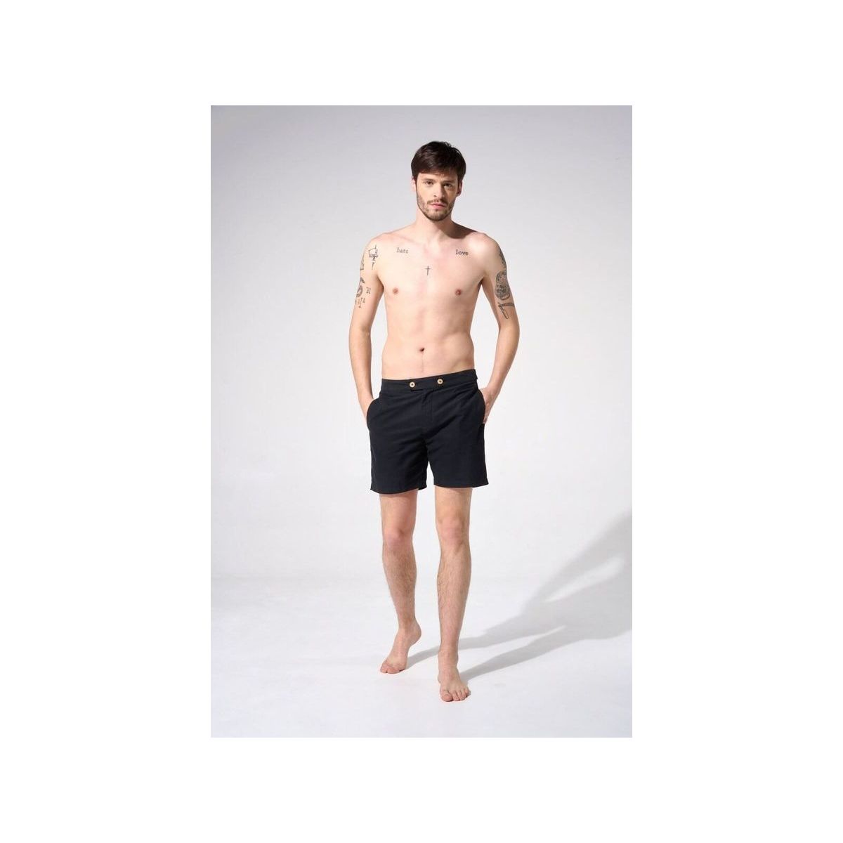 Homme portant des shorts de bain Enzo, couleur noire, avec poches latérales et boutons en gomme.