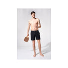 Homme portant le short de bain Enzo, tissu polyester recyclé, poches latérales invisibles, style décontracté.