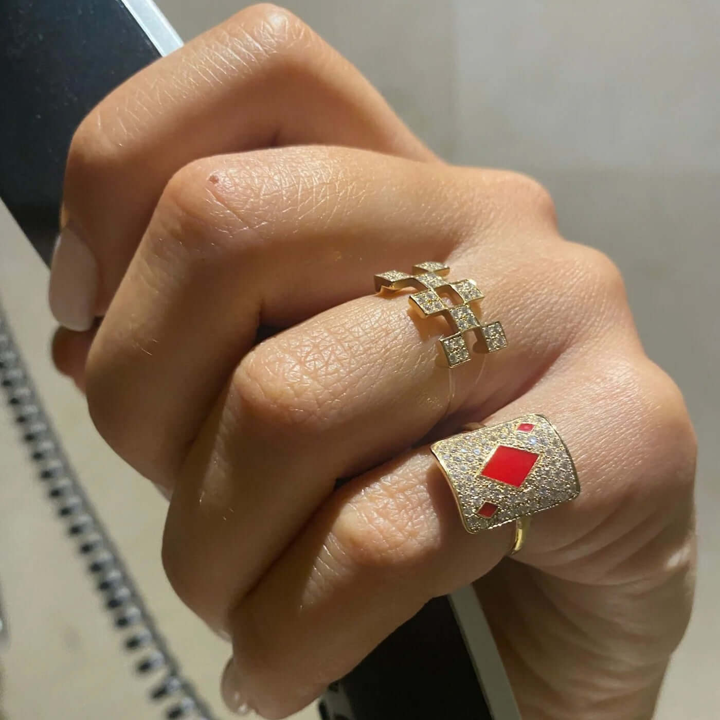 Elegant gold rings adorned with diamonds and red accents, showcasing a stylish hand.