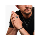 Homme portant une chevalière en argent noirci avec onyx noir, bracelet noir et collier stylé.