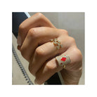 Close-up of a hand wearing two elegant rings, one gold with diamonds and the other with a red gemstone.