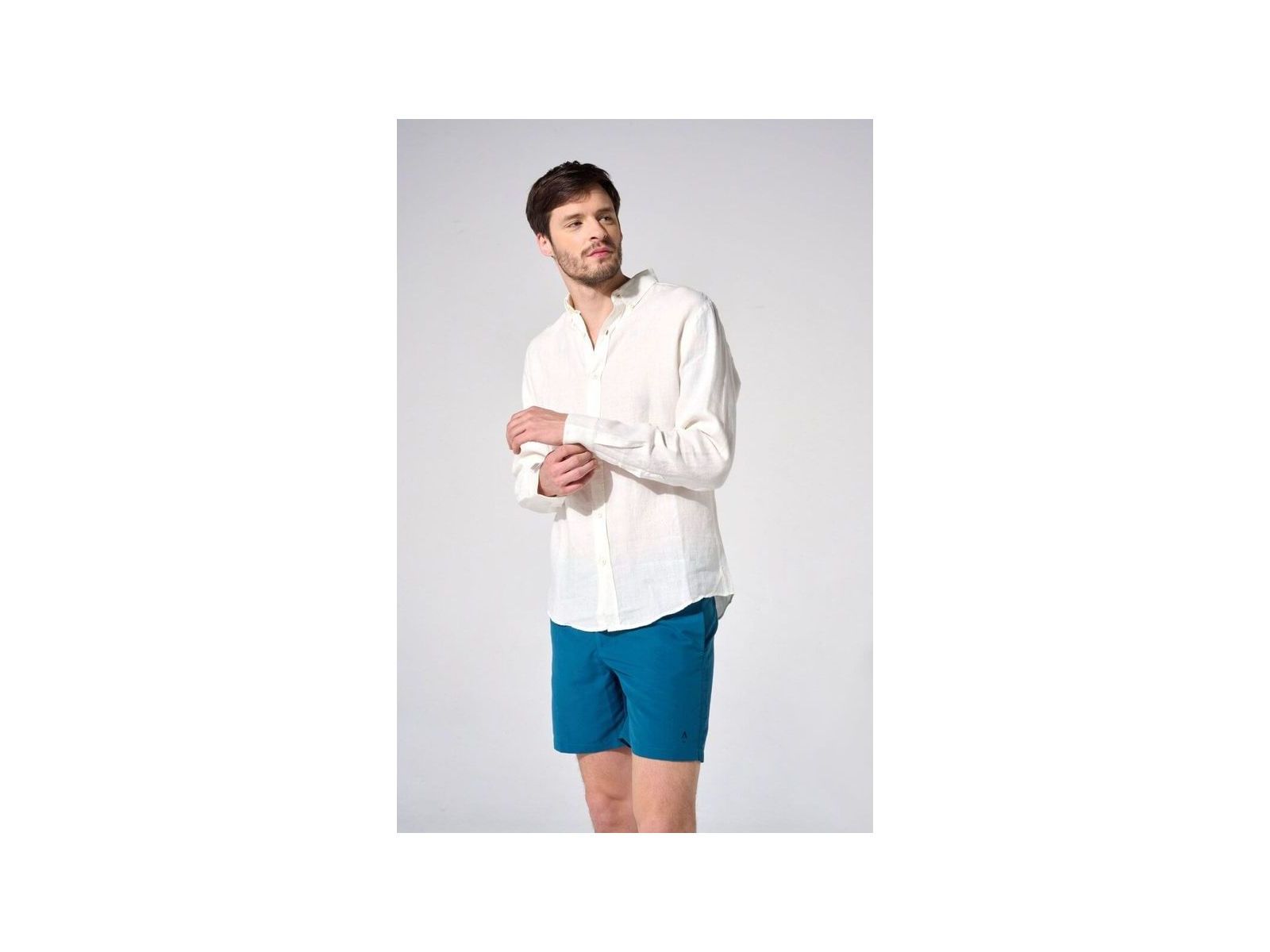 Homme en chemise en lin naturel blanc et short bleu, affichant une coupe classique et élégante.