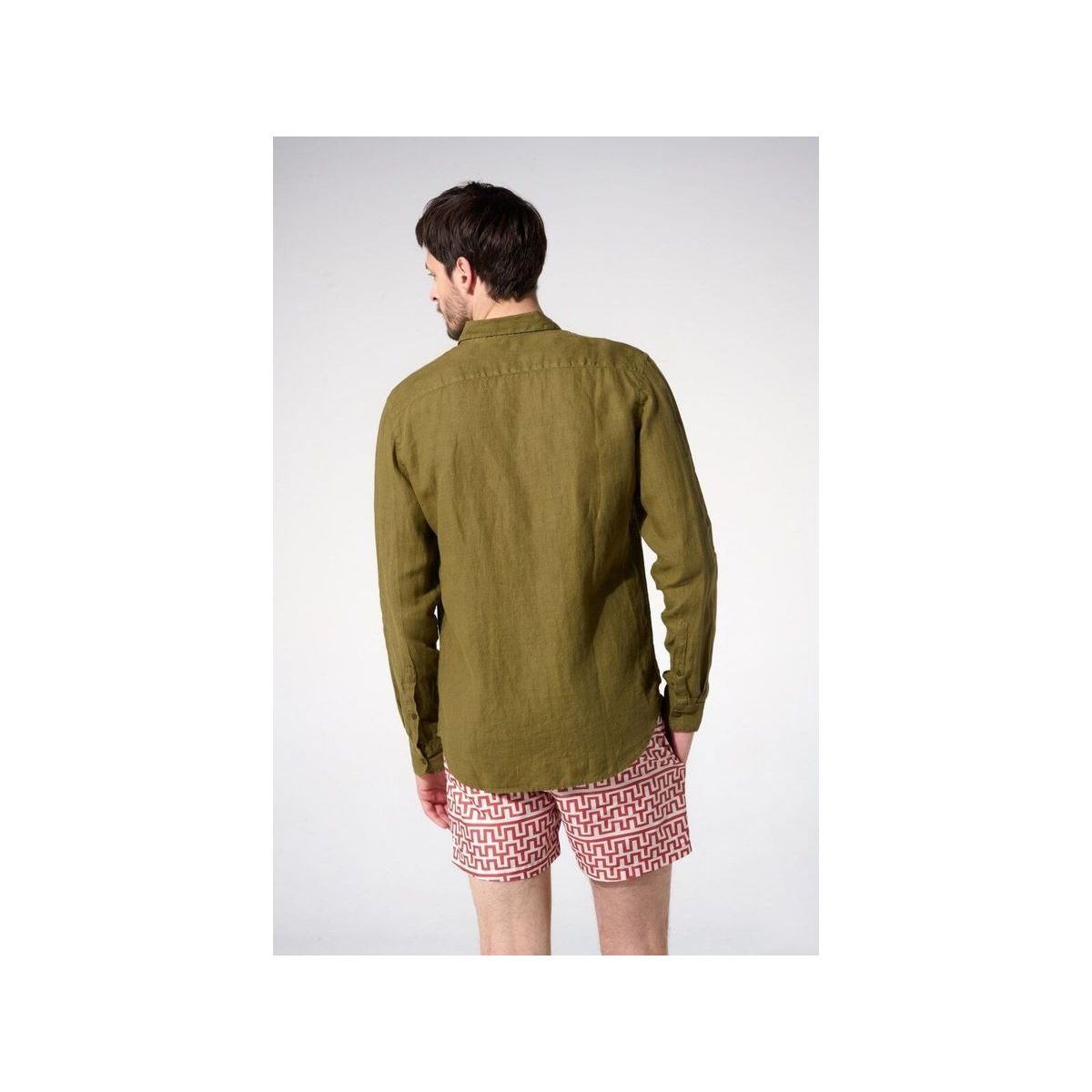 Homme portant une chemise en lin olive vue de dos, associée à un short à motifs.
