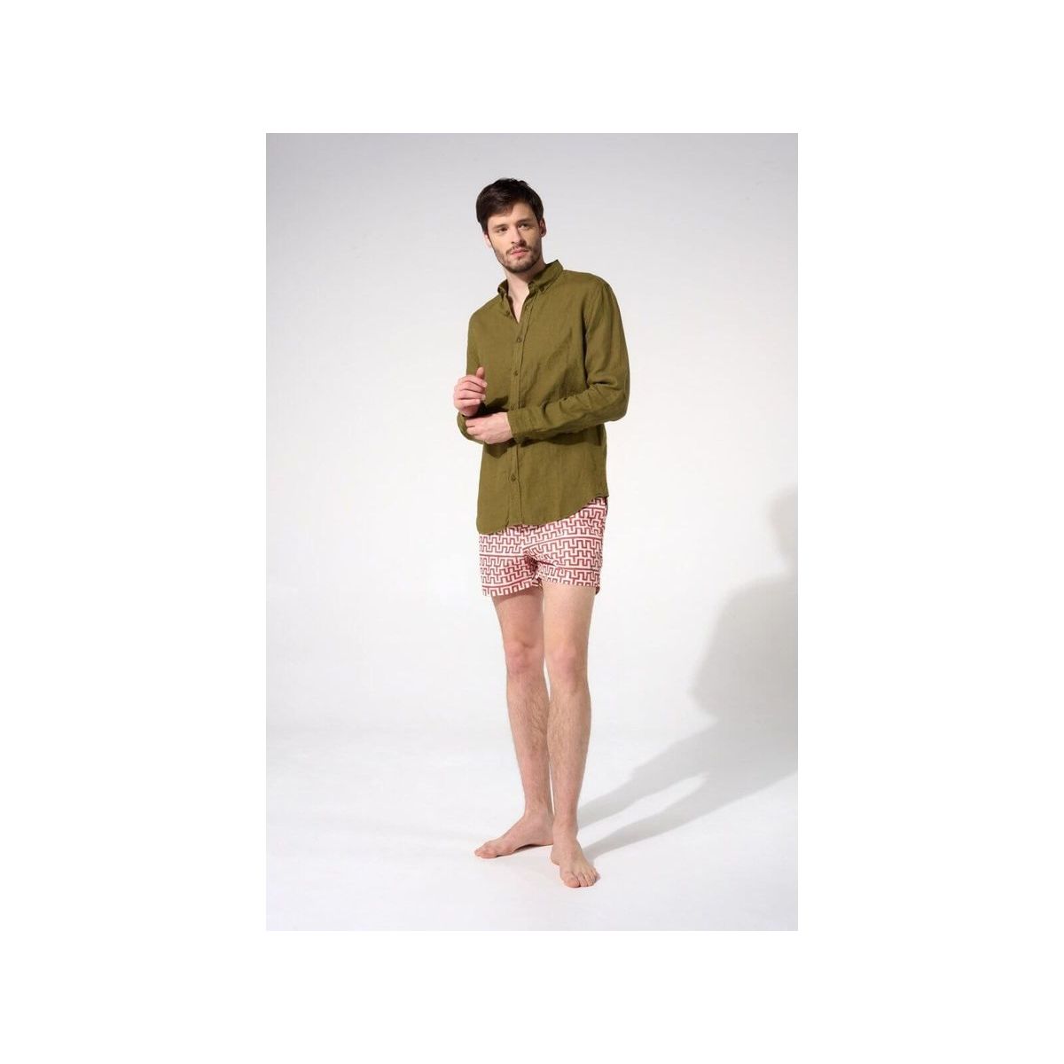 Homme portant une chemise en lin olive avec un pantalon court à motifs, montrant une coupe classique et décontractée.