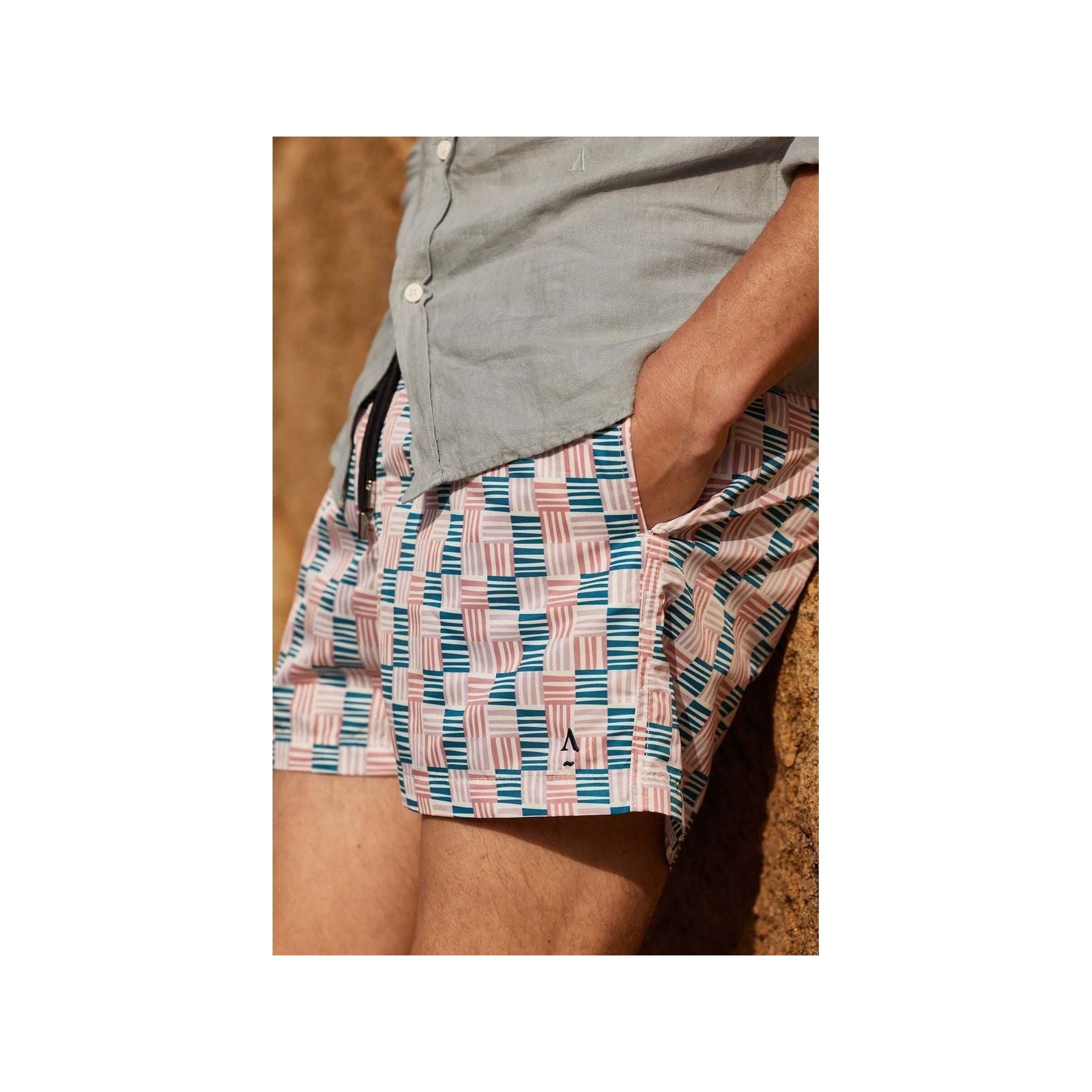 Homme portant des shorts de bain Cannage avec motif géométrique, côté uni, et poche latérale.